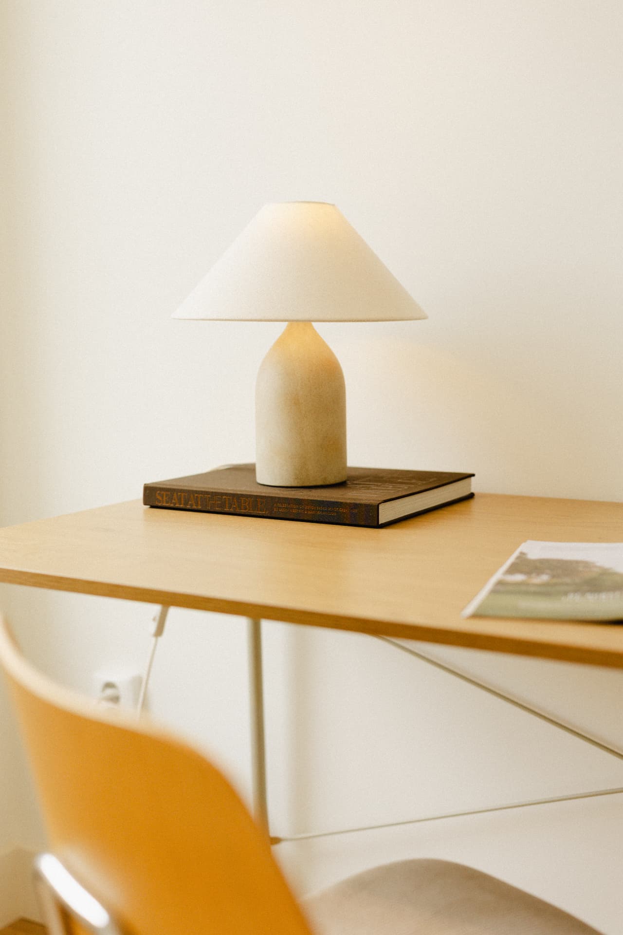 Minimalistische lamp op het boek 'Seat at the Table' op een houten bureau